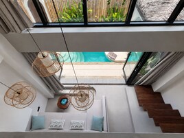 Un interior moderno con una escalera que lleva a un balcón con vistas a una piscina.