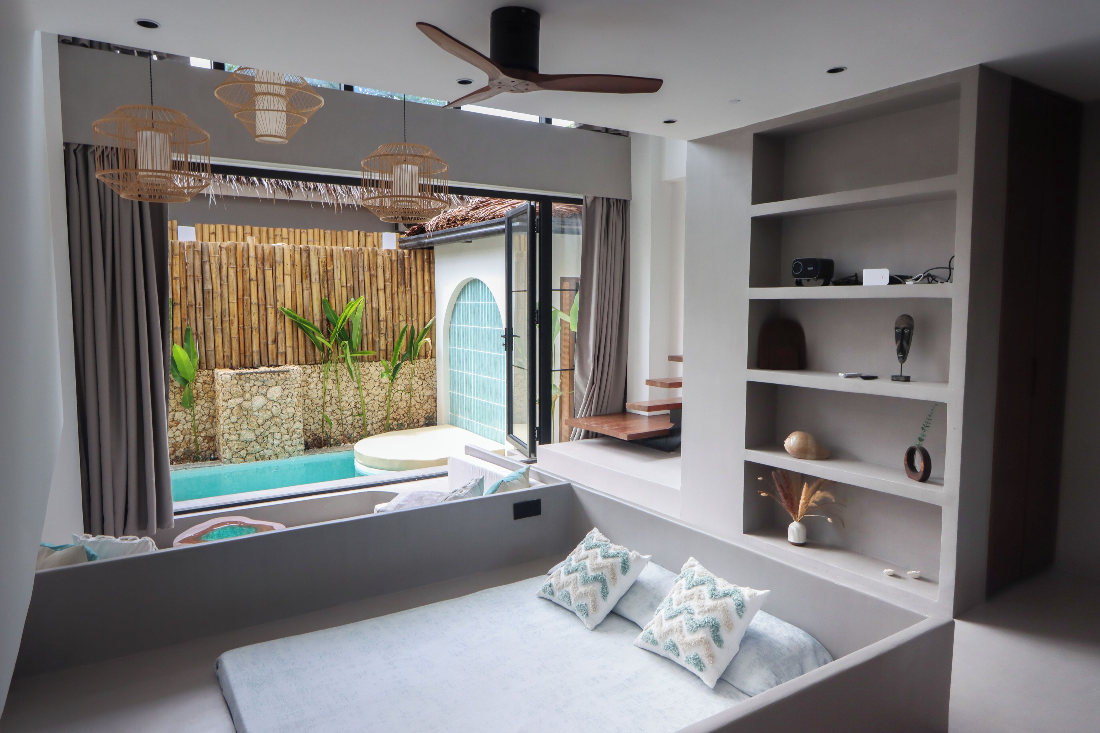 A modern bedroom with a bed, a window, a ceiling fan, and a built-in shelf.
