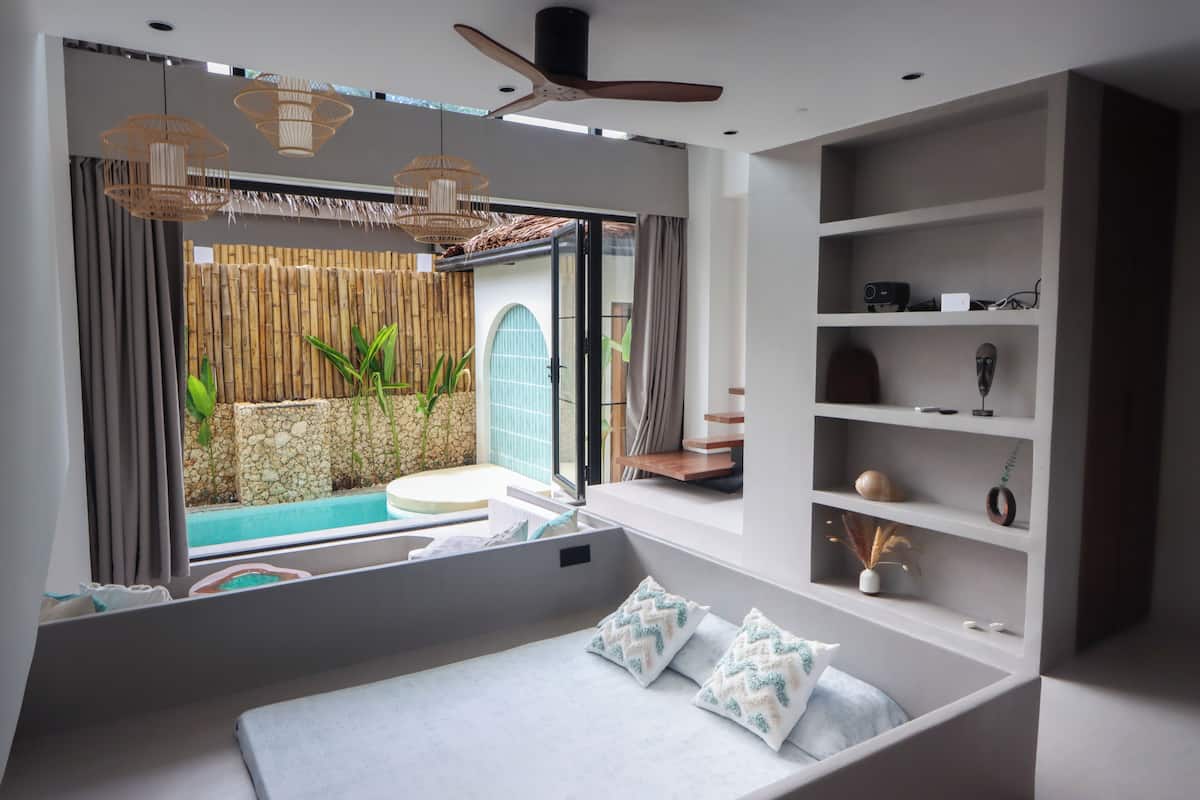 A modern bedroom with a bed, a window, a ceiling fan, and a built-in shelf.