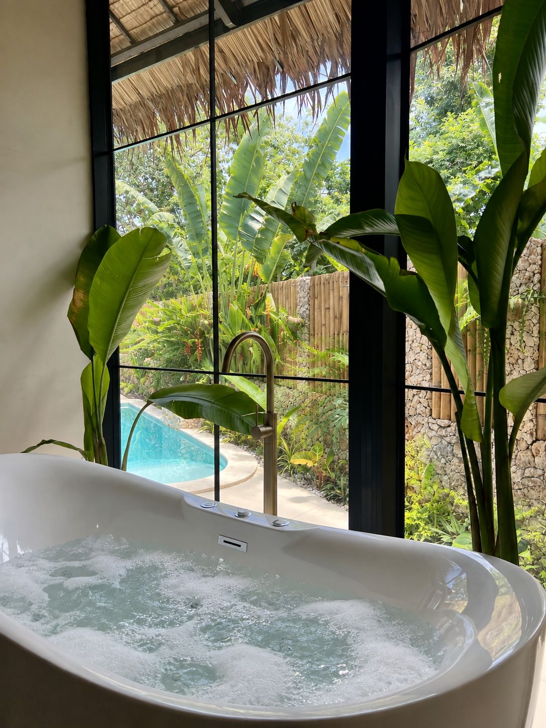 Een jacuzzi met uitzicht op een zwembad en weelderige begroeiing.