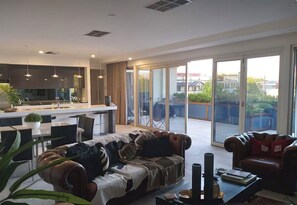 A modern living room with a sofa, a coffee table, and a dining area with a kitchen in the background. - Luxury 2br CBD View Apartment with spectacular balcony! (Kent Town)
