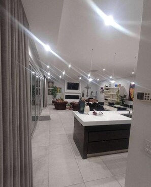 Une cuisine moderne dotée d’un îlot central, de luminaires suspendus et d’une grande fenêtre.