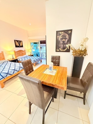 A hotel room with a bed, a dining table with chairs, a vase with flowers, and artwork on the walls. - CONDO W/BALCONY 1 STREET FROM BEACH AND BOARDWALK (Puerto Vallarta)