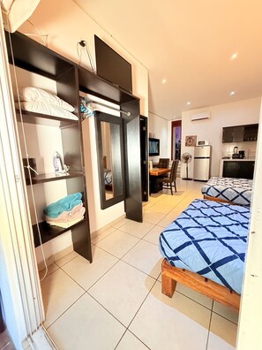 A compact room with a bed, a desk, and a kitchenette. - CONDO W/BALCONY 1 STREET FROM BEACH AND BOARDWALK (Puerto Vallarta)