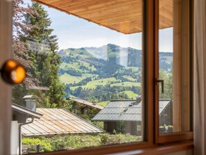 Blick durch ein Fenster auf eine ländliche Landschaft mit sanften Hügeln und blauem Himmel.