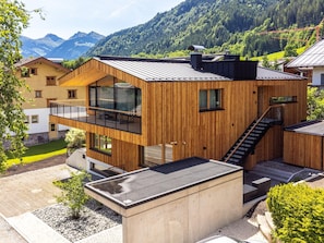 Ein modernes Holzhaus mit Balkon, Treppe und Bergblick.