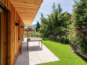 Un bâtiment en bois doté d’un patio couvert, d’une table et d’un mur en pierre.