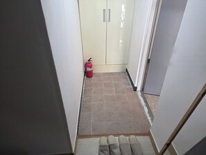 A narrow hallway with a fire extinguisher, a door, and a tiled floor. - Cozy 1-bedroom apartment in tranquil Seoul with AC near Metro Line 2 & 5 (Seoul)