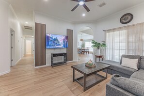 Una sala de estar moderna con un televisor de pantalla plana, un sofá, una mesa de centro y un ventilador de techo.