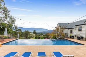 A swimming pool with lounge chairs, a patio area, and a view of mountains. - Mount View Estate - A Luxury Getaway with Unforgettable Views (Yarra Junction)