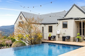 Ein Haus mit Swimmingpool, Sitzgelegenheiten im Freien und Bergblick.