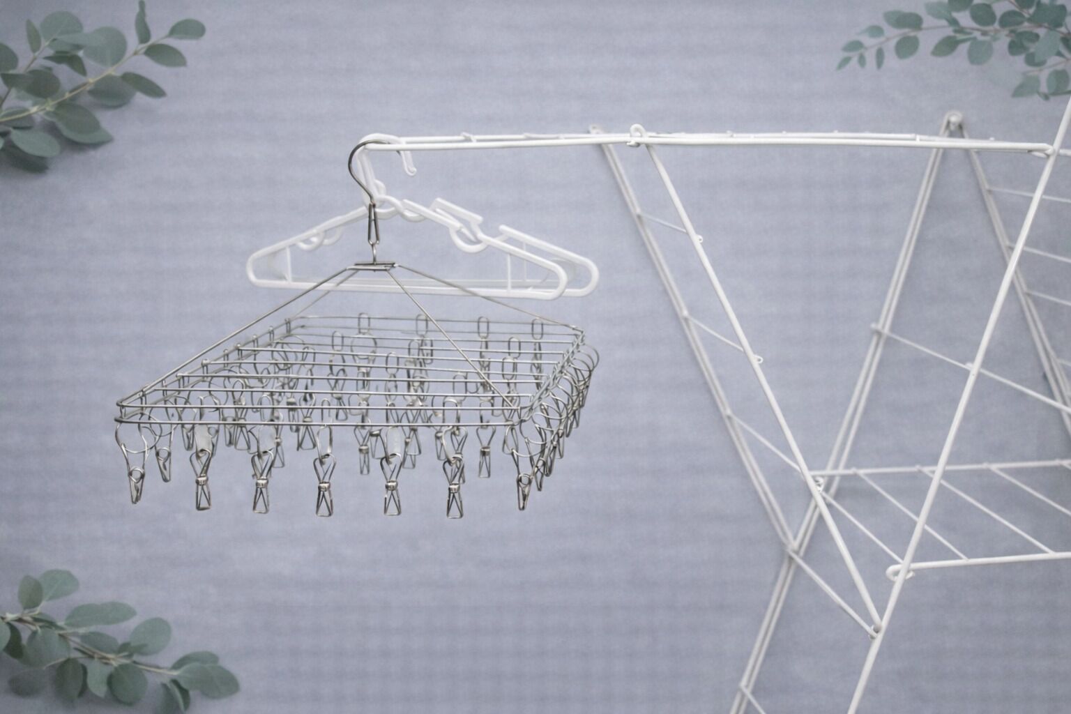 Un tendedero metálico con múltiples clips, colgado de una estructura de metal blanco.