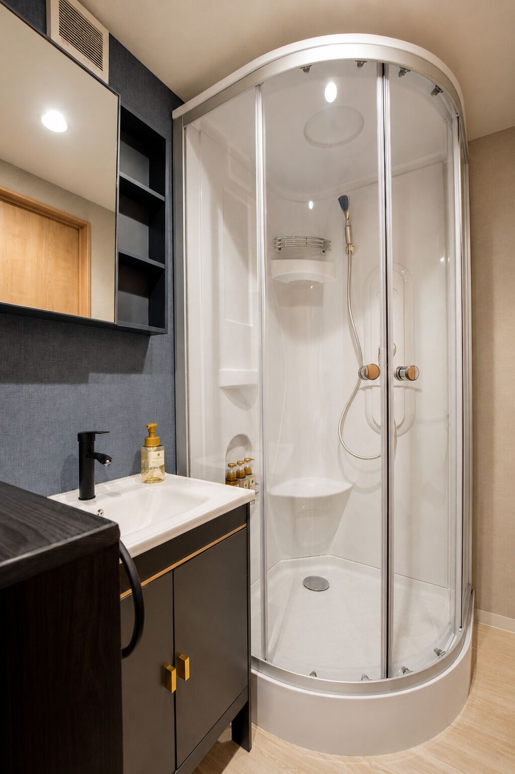 A modern bathroom with a glass-enclosed shower, a white sink, and dark-toned cabinets.