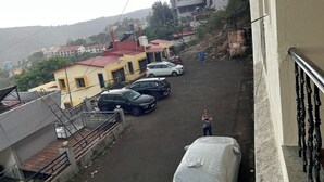 Et boligområde med parkerede biler og en person på en balkon.