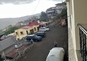 A residential area with parked cars and a person standing on a balcony.