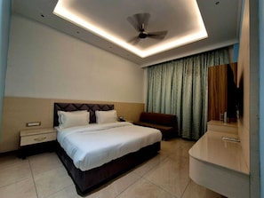 A modern hotel room with a bed, bedside table, nightstand, and a mirror. - Hotel Satyaki Orchid (Katra)