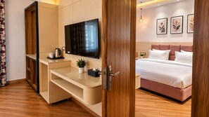 A hotel room with a bed, a TV, a desk, and a bedside table. - Hotel Satyaki Orchid (Katra)