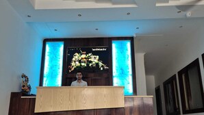 A reception desk with a digital display above it. - Hotel Satyaki Orchid (Katra)