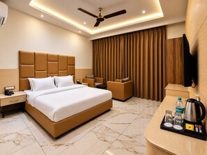 A hotel room with a bed, seating area, and a desk with amenities. - Hotel Satyaki Orchid (Katra)