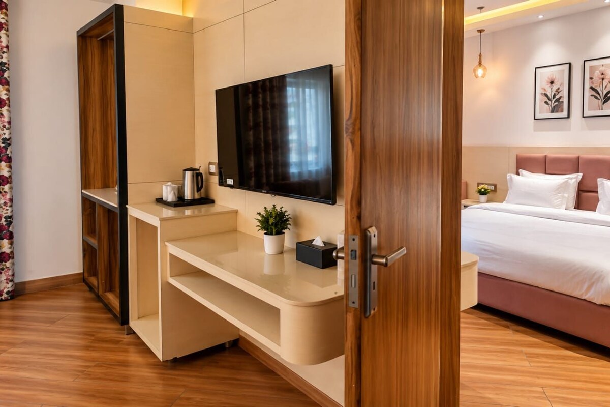 A hotel room with a bed, a TV, a desk, and a bedside table.