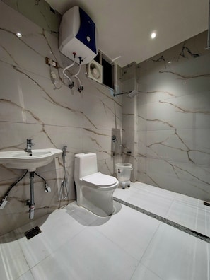 A modern bathroom with a white toilet, a sink, and a shower. - Hotel Satyaki Orchid (Katra)