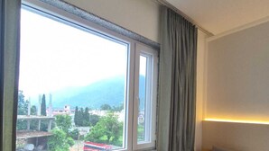 A room with a large window, two yellow armchairs, a small wooden table, and a grey sofa. - Hotel Satyaki Orchid (Katra)