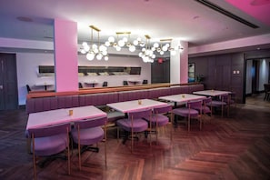 Un ristorante moderno con un bancone centrale, posti a sedere tipo cabina e tavoli.
