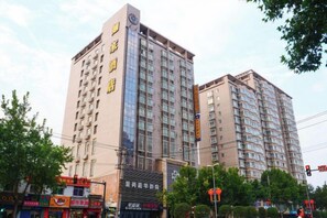 Un hotel de varios pisos con un letrero llamativo en la fachada, múltiples ventanas y una entrada visible.
