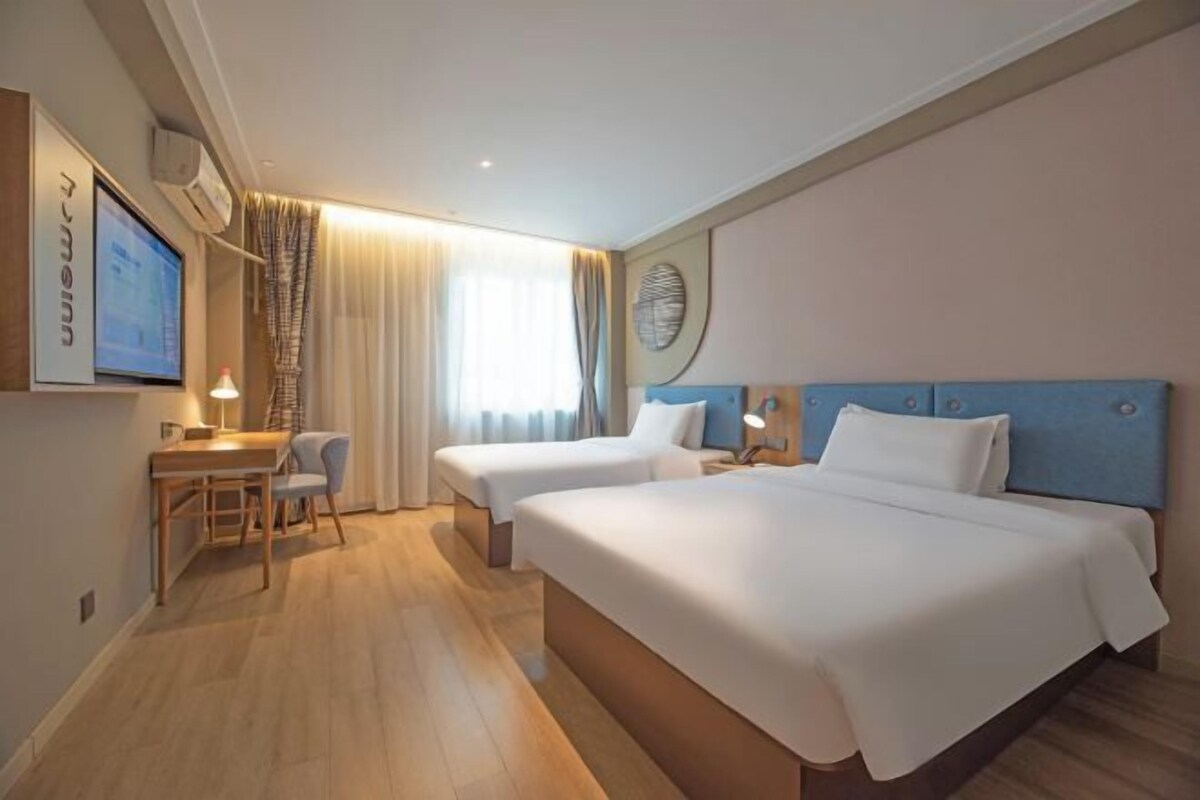 Ein Hotelzimmer mit zwei Betten, einem Schreibtisch und einem Fernseher.