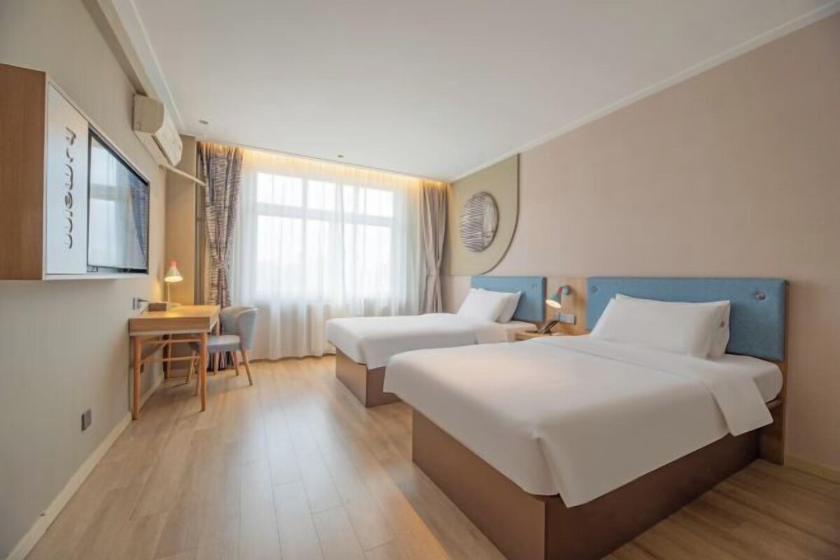 Ein Hotelzimmer mit zwei Betten, einem Schreibtisch und einem Fernseher.