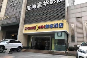 Entrada de un hotel con un cartel que dice 'HOME INN' y una puerta de acceso visible.