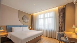 A hotel room with a large bed, a desk, a chair, a round wall decoration, and a window with curtains. - Home Inn (Xi'an Big Wild Goose Pagoda Xiying Road) (Xi'an)