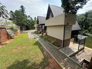 A modern building with a flat roof, a paved walkway, and a small garden area.