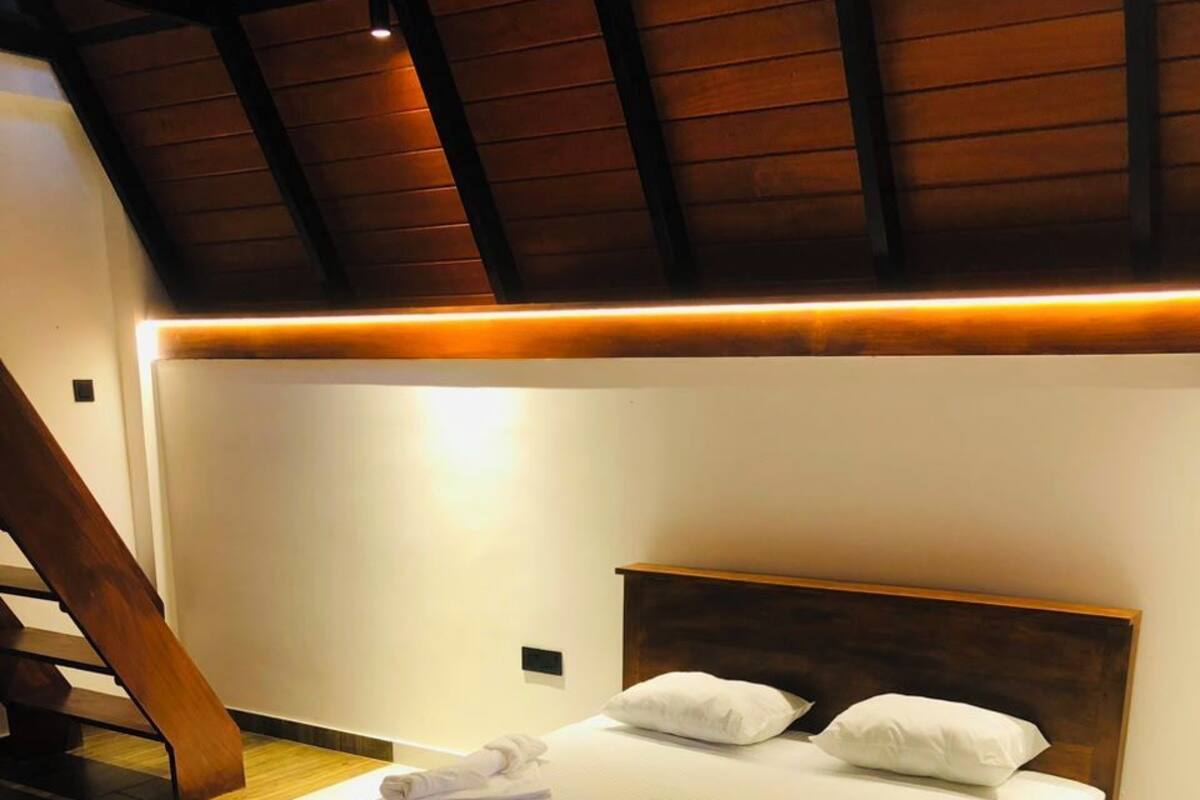 Une chambre à coucher avec un lit en bois, du linge de lit blanc et une tête de lit en bois.