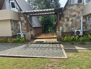 A building entrance with a stone facade, a covered walkway, and two air conditioning units.
