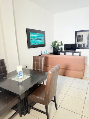 A dining area with a table, chairs, a sofa, and a TV. - CONDO W/ BALCONY JUST STEPS FROM BEACH N BOARDWALK (Puerto Vallarta)