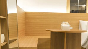 A modern bathroom with wooden walls, a round wooden table, and a white towel dispenser. - Hotel GEUMO on (Gumi)