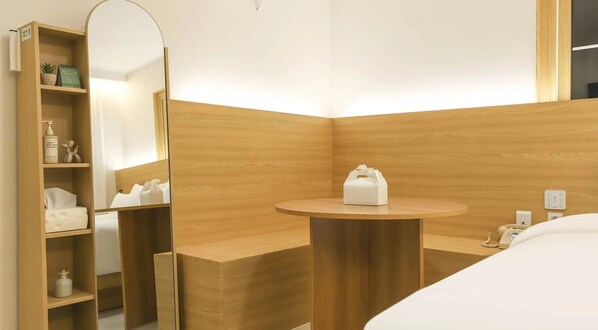 Un baño moderno con tocador de madera, un espejo redondo y una mesita de noche con artículos de aseo.