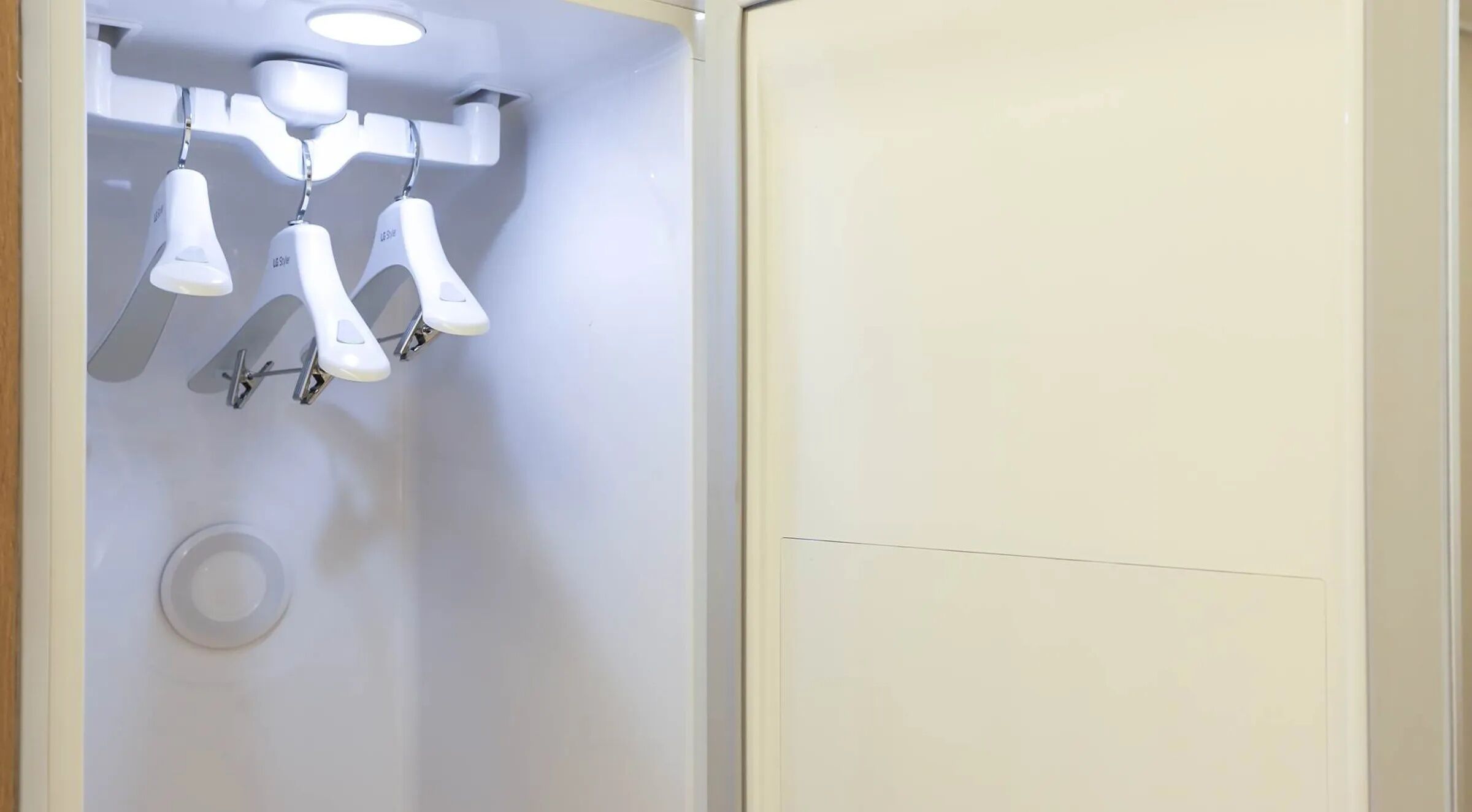 Un baño con pared blanca, una lámpara en el techo y una puerta blanca.