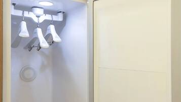 Un baño con pared blanca, una lámpara en el techo y una puerta blanca.