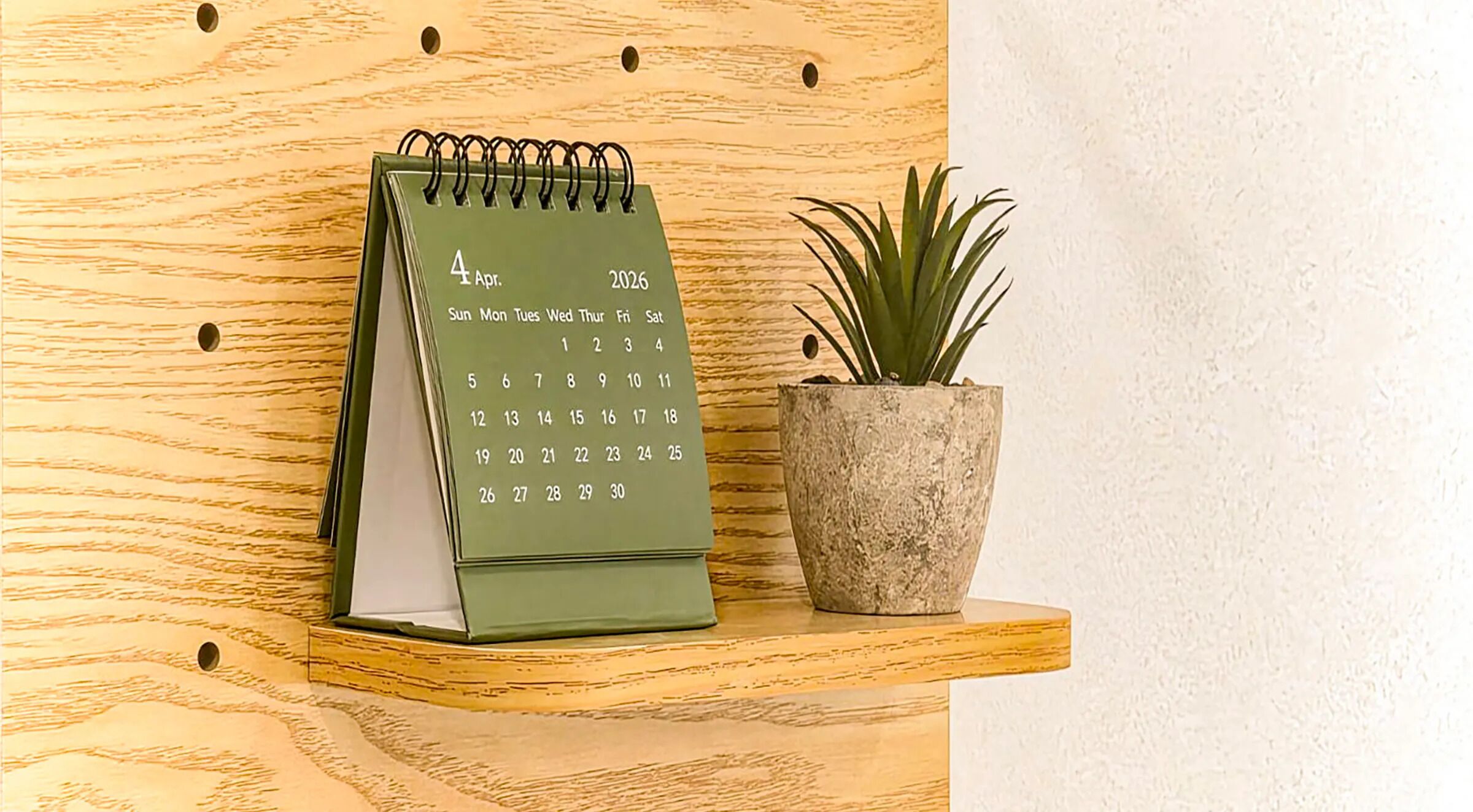 A green desk calendar with a plant beside it.