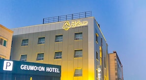Un edificio de hotel con un letrero que dice 'GEUMO:ON HOTEL' y un cartel de estacionamiento debajo.