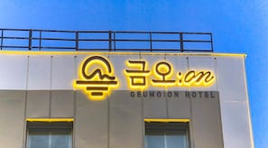 A hotel sign with illuminated neon letters and a metal railing above. - Hotel GEUMO on (Gumi)