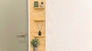 A wooden wall with shelves holding a calendar, a small plant, and a vase. - Hotel GEUMO on (Gumi)