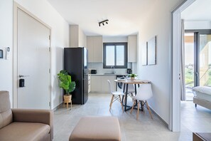 A modern apartment with a kitchenette, dining area, and a living space with a sofa and ottoman. - Park View Retreat Limassol Pool & Free Parking (Limassol)