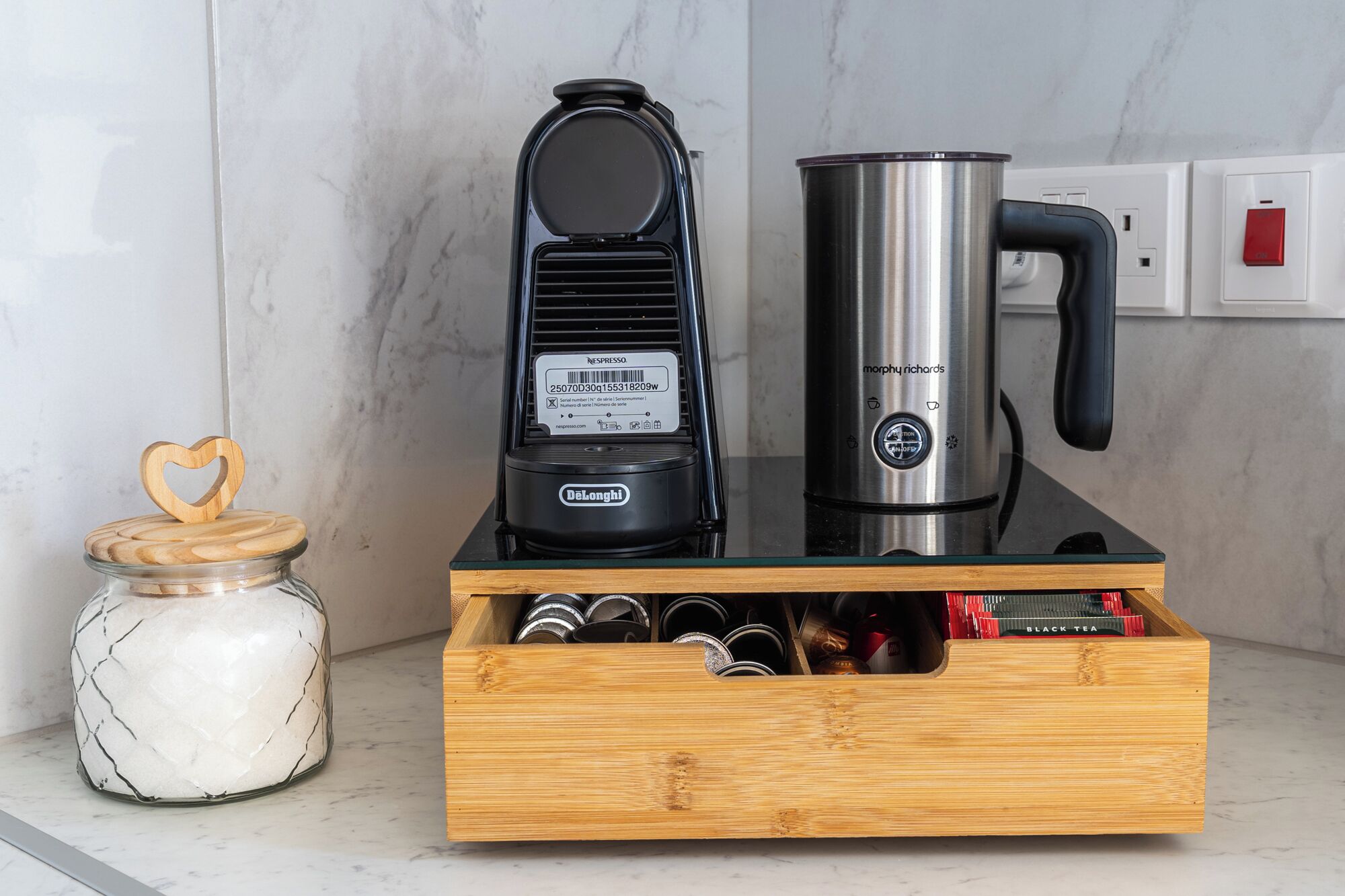 Une cuisine équipée d’une machine à café, d’une bouilloire et d’un tiroir contenant des boîtes de thé.