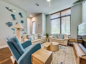 Ein Wohnzimmer mit einem blauen Sofa, einem Holztisch und einem gemusterten Teppich.