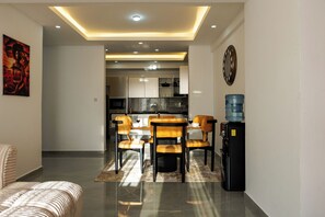 Un salon moderne avec un coin repas, une cuisine à l’arrière-plan et un distributeur d’eau.