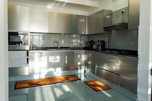 Une cuisine moderne équipée d’appareils électroménagers en acier inoxydable, d’un évier et d’une hotte aspirante.