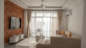 Una sala de estar moderna con un sofá, televisor y ventilador de techo.